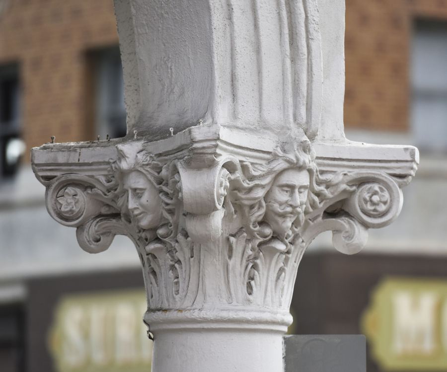 A white column top carved with faces and scrolls.