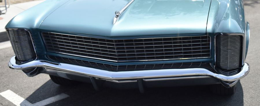 The front grille and chrome bumper of a light blue classic car.