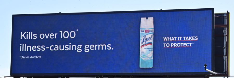 A digital billboard advertising Lysol spray against a blue sky, with a spray can pictured on the right.