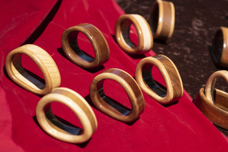 Wooden bracelets with dark inlays displayed on red fabric.
